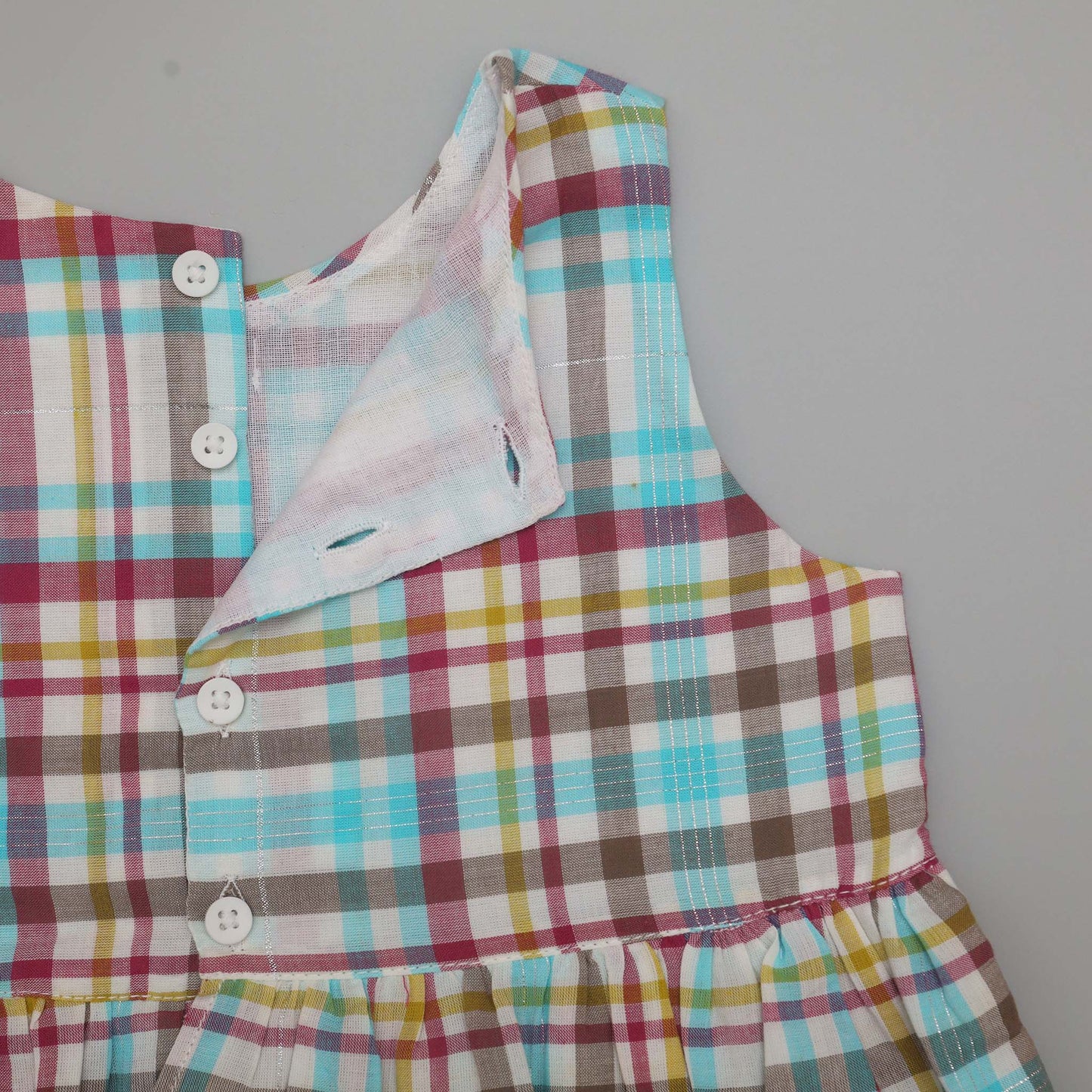 Multicolored plaid dress with buttons on a plain background