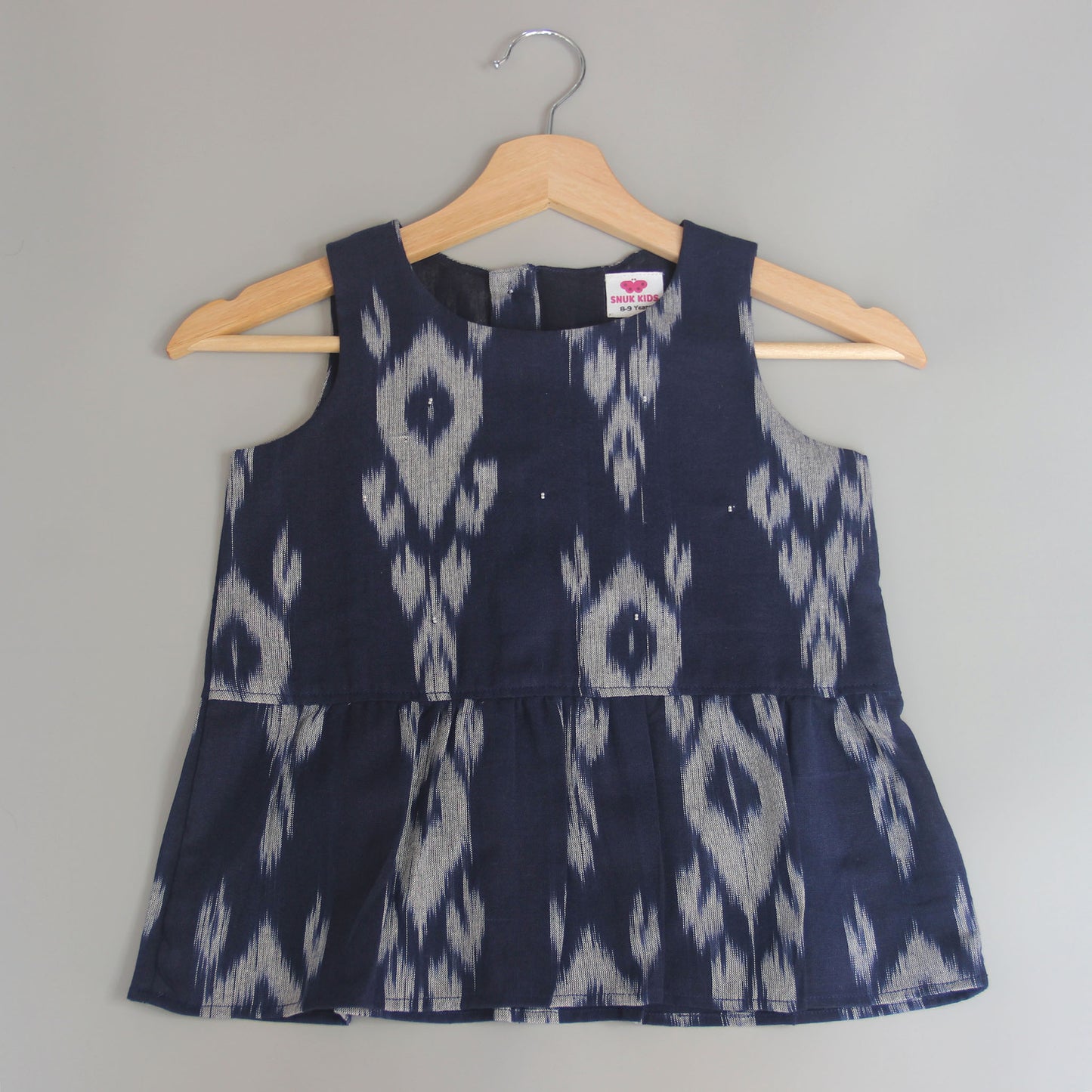 Navy blue dress with white pattern on a hanger against a gray background