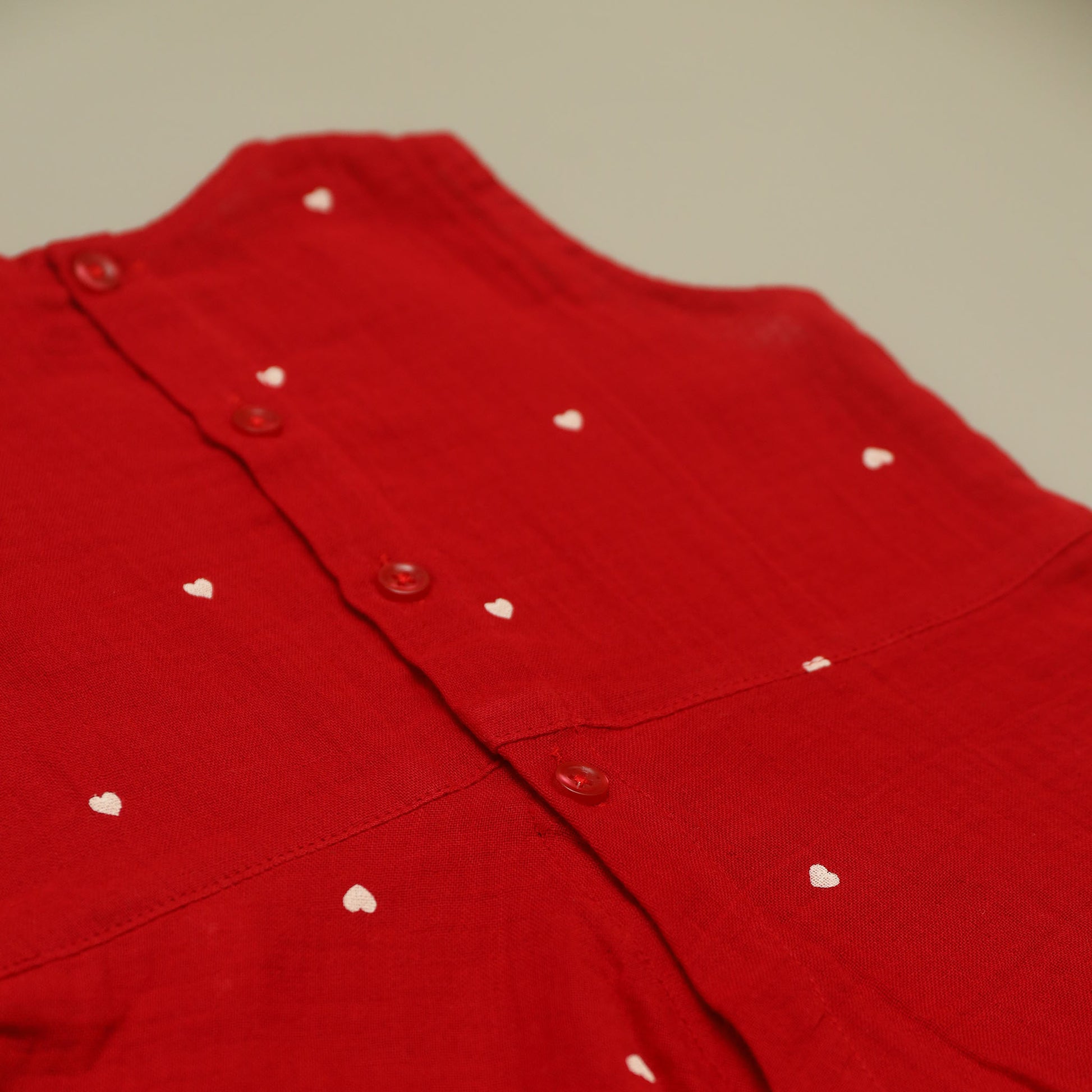 Red garment with white heart patterns on a neutral background