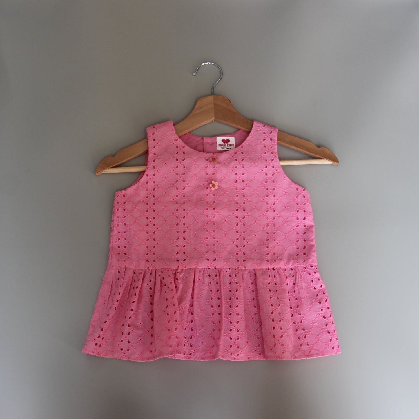 Pink dress on a hanger against a gray background