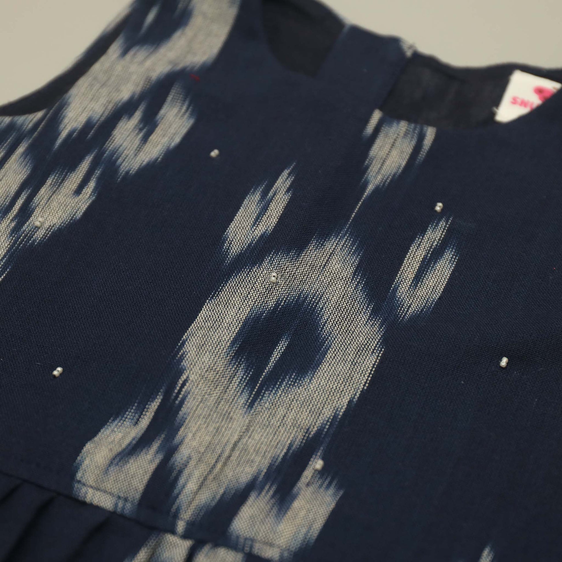 Navy blue fabric with ikat and small white stones on a neutral background