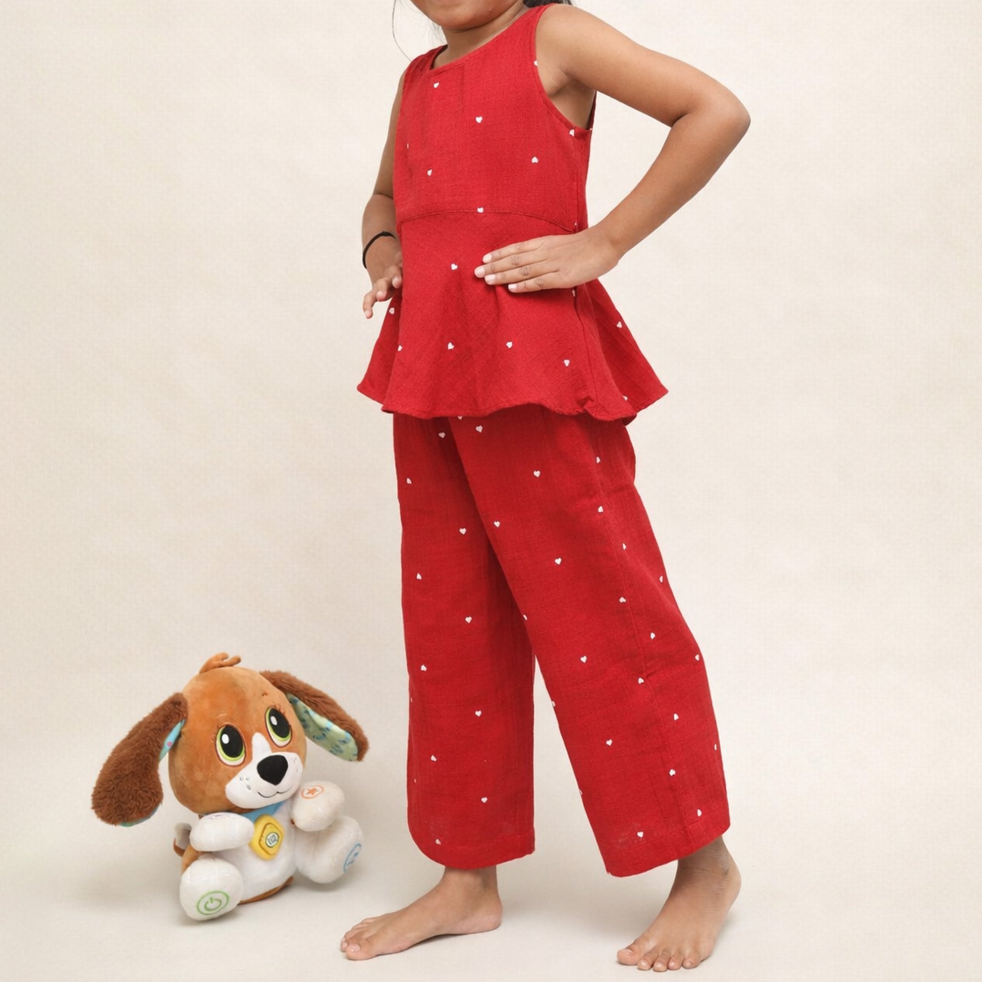 Child wearing red pajama set with white heart.