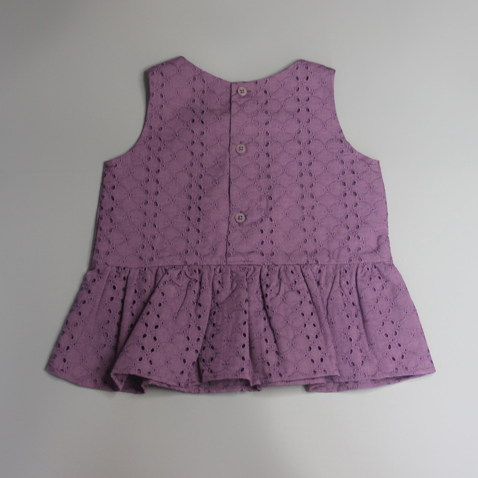 Purple sleeveless top with button details on a gray background
